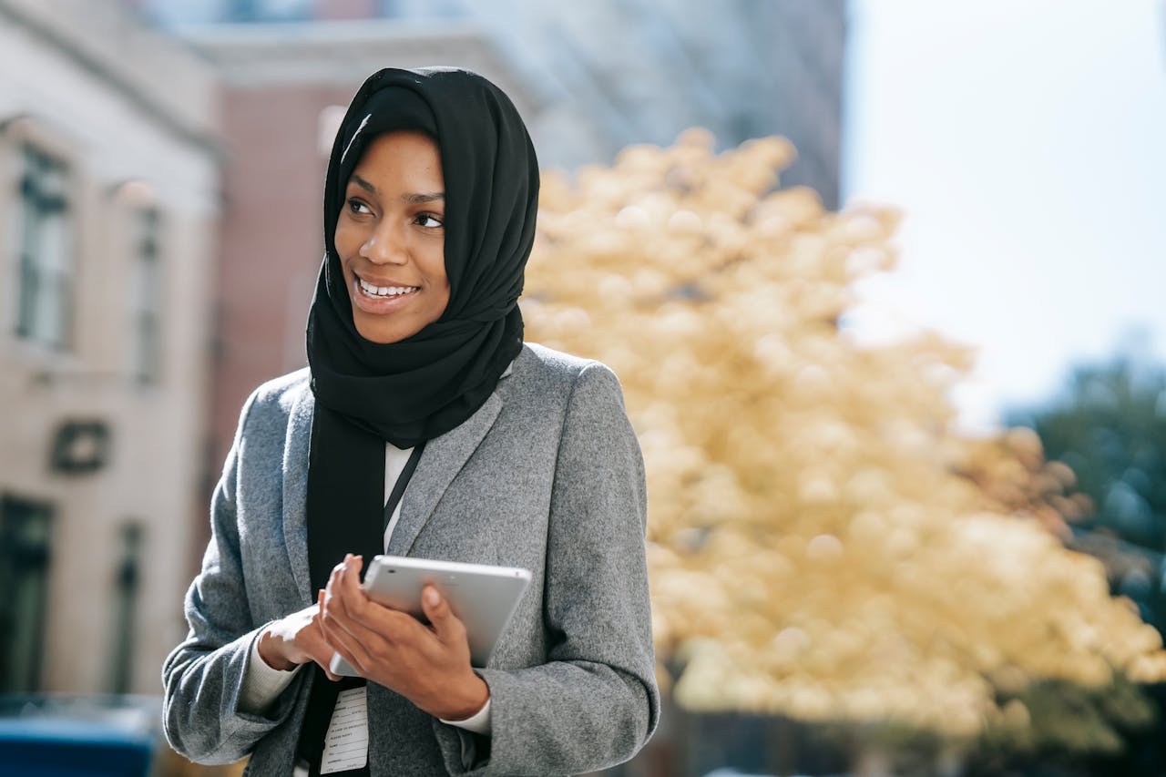 Confident businesswoman with a tablet, enjoying a sunny day in the city.